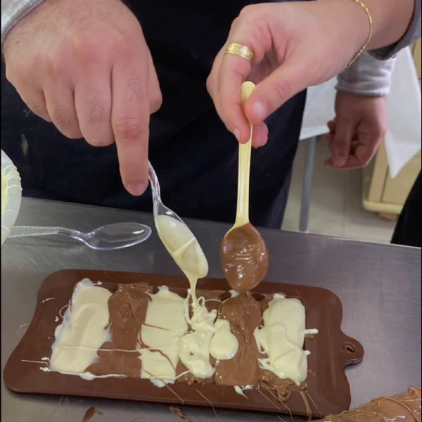 משתתפים בסדנת שוקולד של שוקוליב יוצרים טבלת שוקולד מעוצבת בשילוב אמנותי של שוקולד חלב ושוקולד לבן