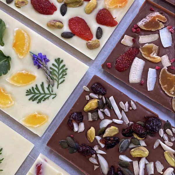 טבלאות שוקולד לבן וחלב מעוצבות עם תוספות של פירות יבשים, אגוזי פיסטוק, גרעינים ופרחים אכילים, תוצרת שוקוליב