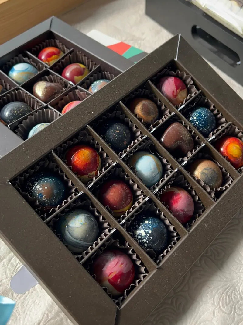 מבחר פרלינים צבעוניים בעבודת יד בעיצובים אמנותיים, מתוך סדנת השוקולד של שוקוליב